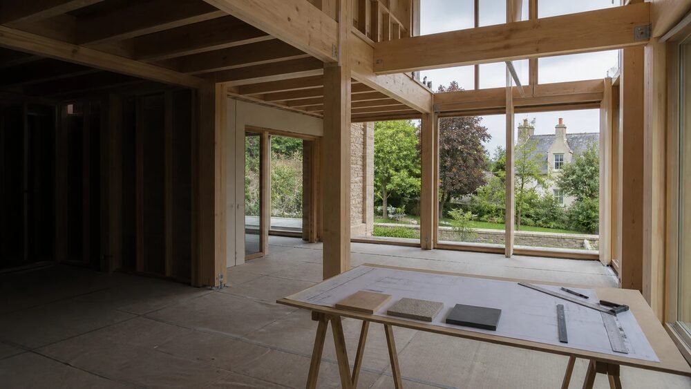 Intérieur vide d’une maison en structure bois avec plans et échantillons préparés sur une table