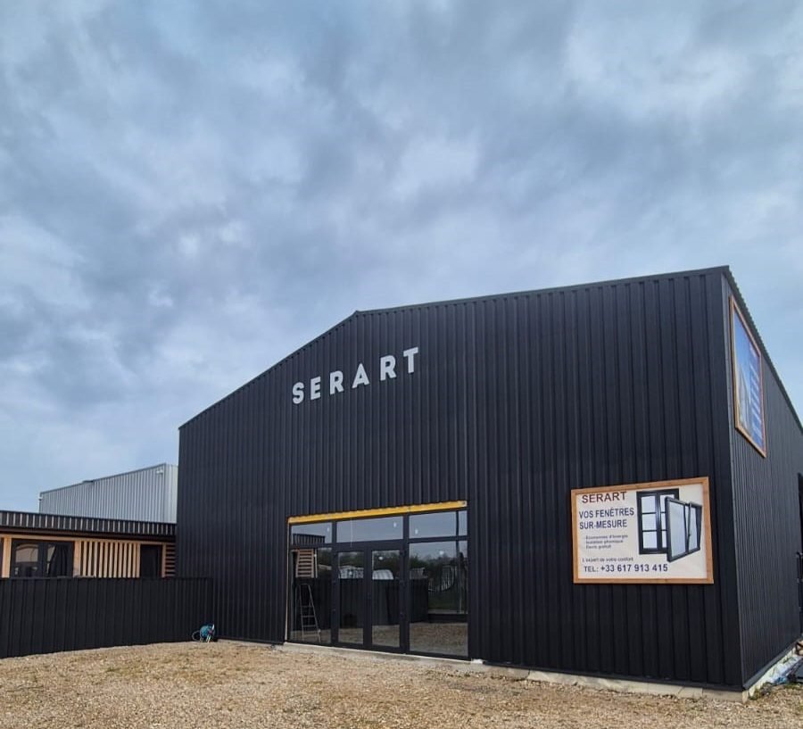 L’atelier SERART à Bray-sur-Seine, bâtiment à bardage métallique noir nervuré, pignon asymétrique et entrée vitrée
