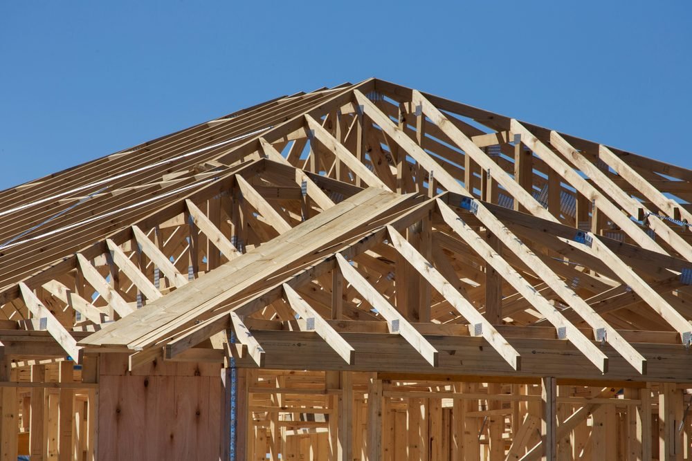 Charpente en bois d’une maison en construction : fermes, pannes et contreventements assemblés, sous un ciel dégagé