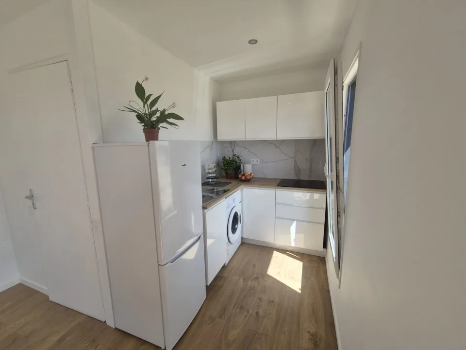 Cuisine équipée avec façades blanches laquées, crédence effet marbre, plan de travail bois, plaque de cuisson et lave-linge