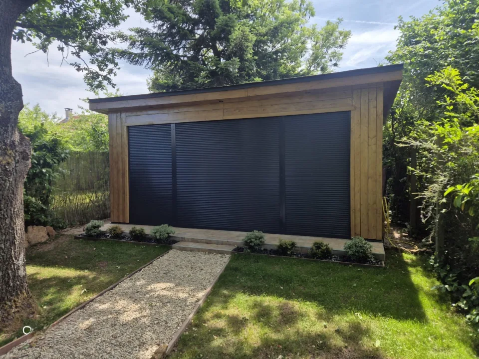 Studio livré volets roulants fermés, allée gravillonnée et massifs plantés au pied de la terrasse