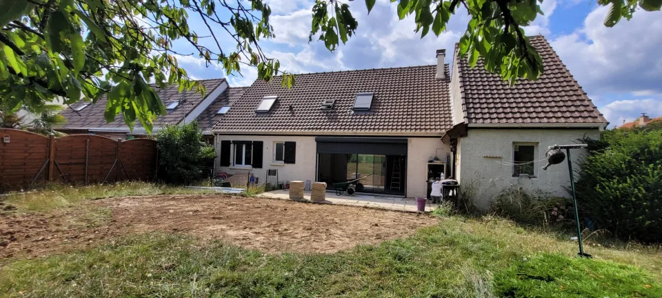 Vue large de l’arrière de la maison et des maisons voisines, terrain préparé devant la façade avant la pose de la terrasse