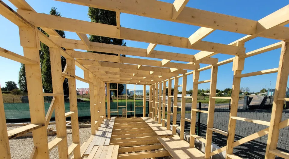 Ossature bois vue de l’intérieur pendant le montage, montants, solives de plafond et plancher en cours de pose
