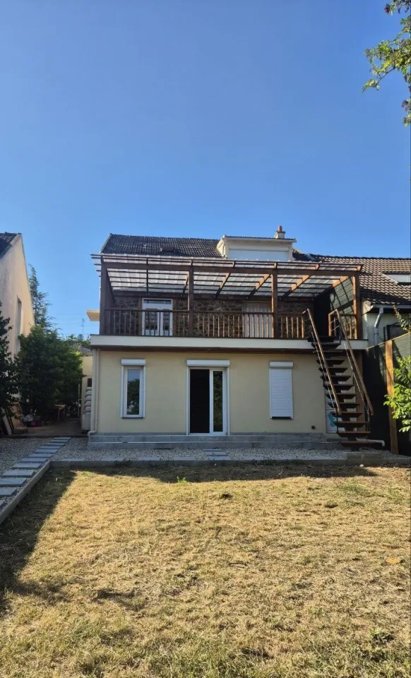 La façade arrière depuis la pelouse, l’extension au rez-de-chaussée et la terrasse sous pergola au-dessus