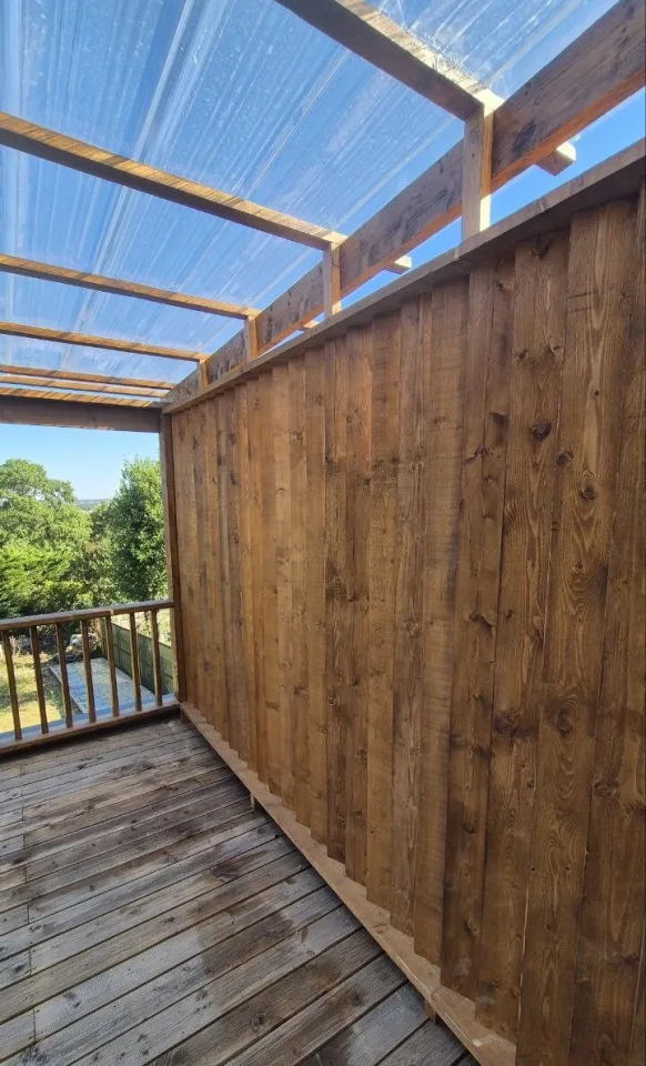 Pare-vue en lames de bois verticales le long de la terrasse, sous la pergola